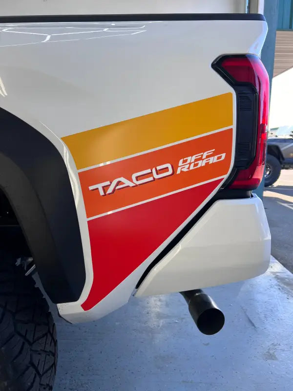 White pickup truck with retro-style lower bedside decals for 2024 Tacoma TACO Graphics