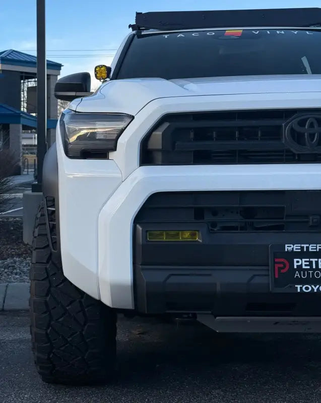 White Toyota Tacoma front with 2025+ 4Runner fog light overlays on headlights