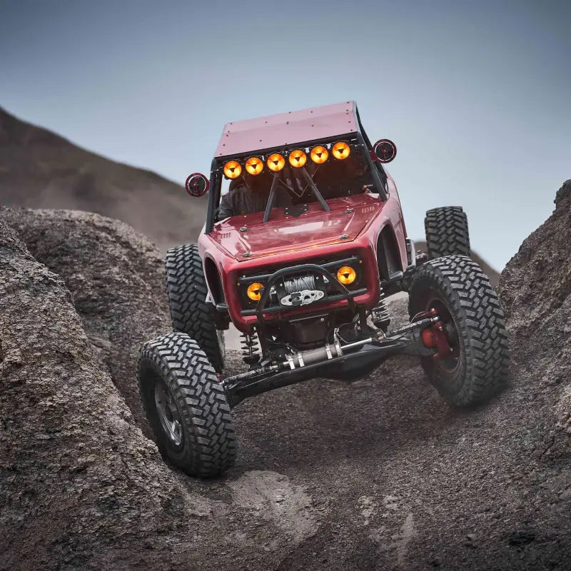 Red off-road vehicle climbing rocky terrain with Titan™ LED Light Bar, demonstrating its reliability in extreme conditions.