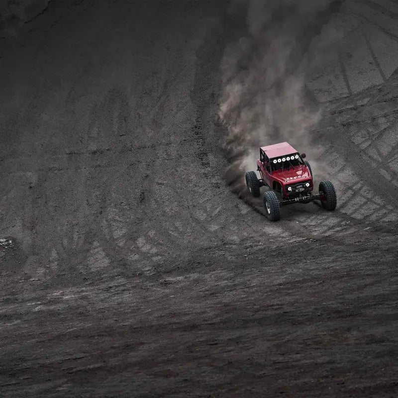 Aerial view of red off-road vehicle with Titan™ LED Light Bar navigating a dusty trail, highlighting its performance.