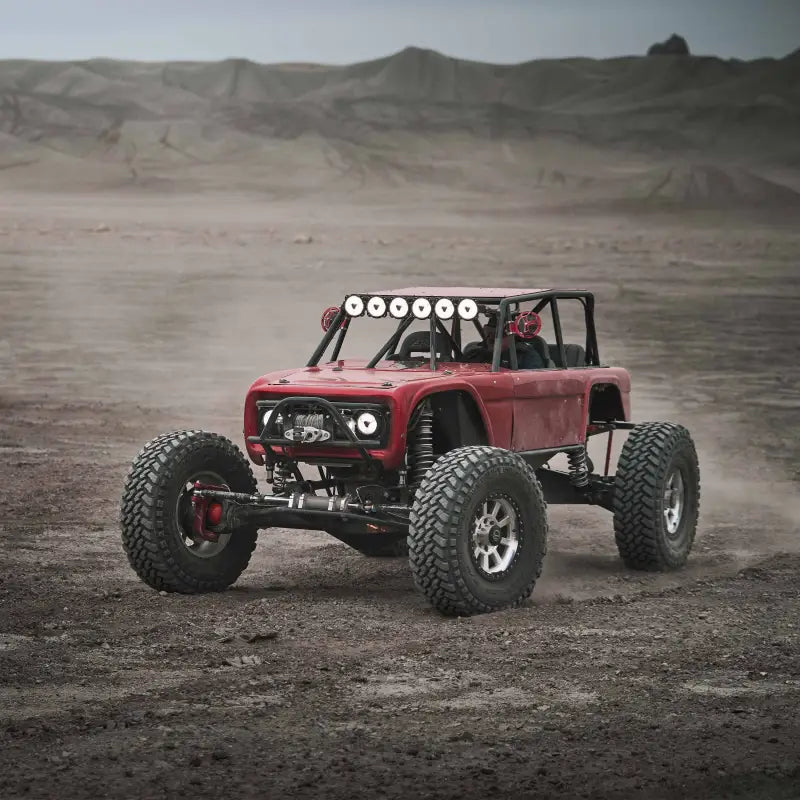 Red off-road vehicle in a desert landscape equipped with Titan™ LED Light Bar, emphasizing its lighting performance.