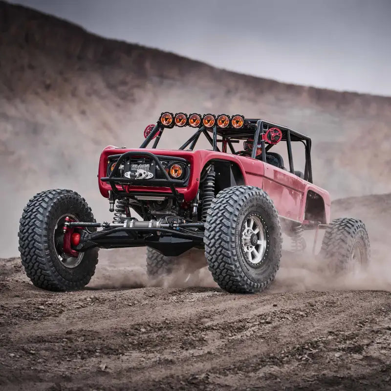 Red off-road vehicle with Titan™ LED Light Bar driving through rugged terrain, showcasing its off-road capabilities.