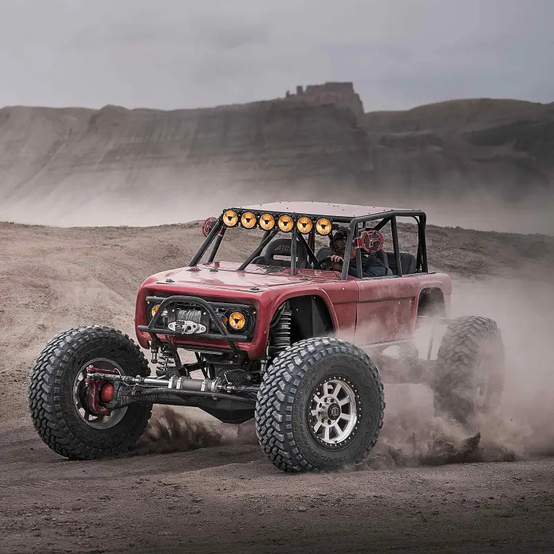 Red off-road vehicle with Titan™ LED Light Bar driving through dusty terrain, highlighting its durability and lighting power.