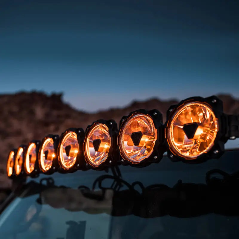 Close-up of the 50-inch Gravity Titan LED Light Bar mounted on a vehicle, emitting amber light for off-road visibility.