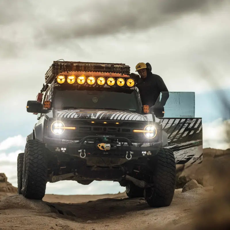 Off-road vehicle with the 50-inch Gravity Titan LED Light Bar mounted on the roof, emitting amber light in rugged terrain.