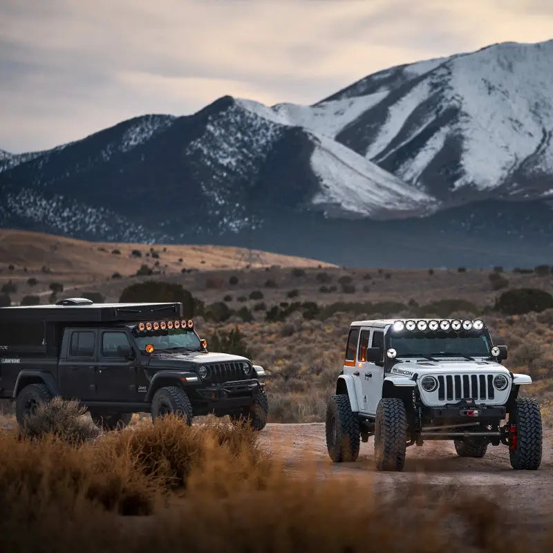 Two off-road vehicles equipped with the 50-inch Gravity Titan LED Light Bar parked in a scenic mountain landscape.