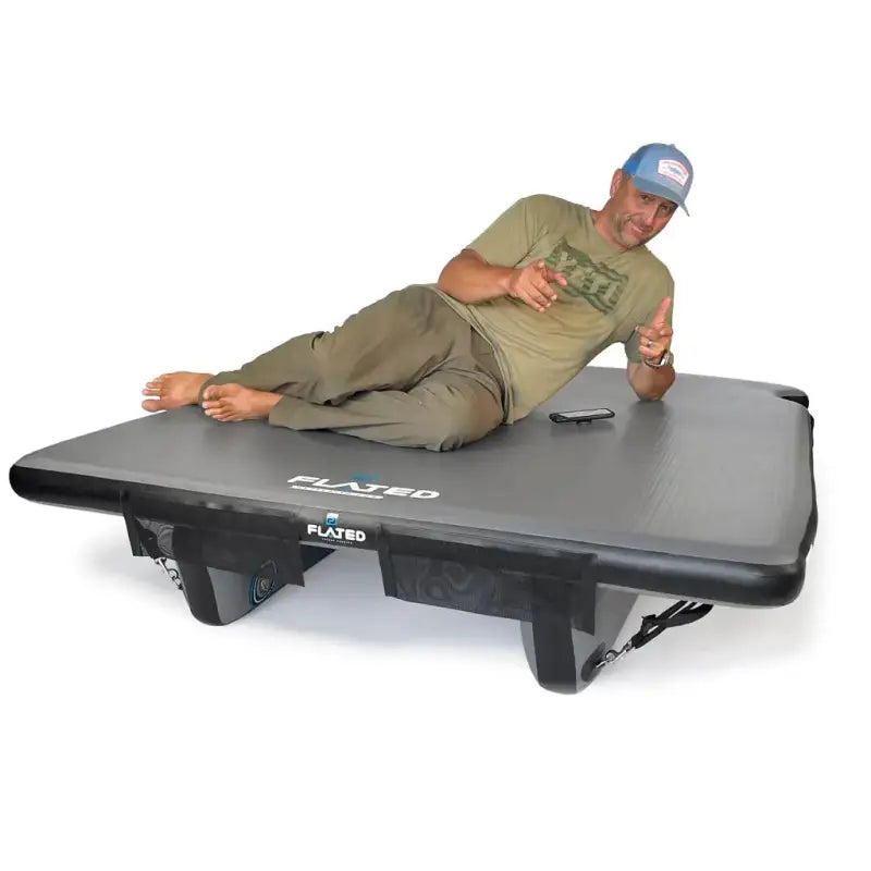 Man reclining on the 6' Cot - Portable Air-Deck, showcasing its sturdy and comfortable design for camping or outdoor relaxation.