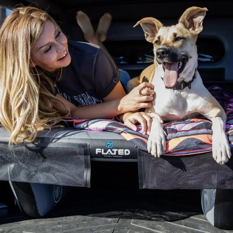 Woman and dog relaxing on the 6' Cot - Portable Air-Deck in a truck bed, showcasing comfort and durability for outdoor adventures.