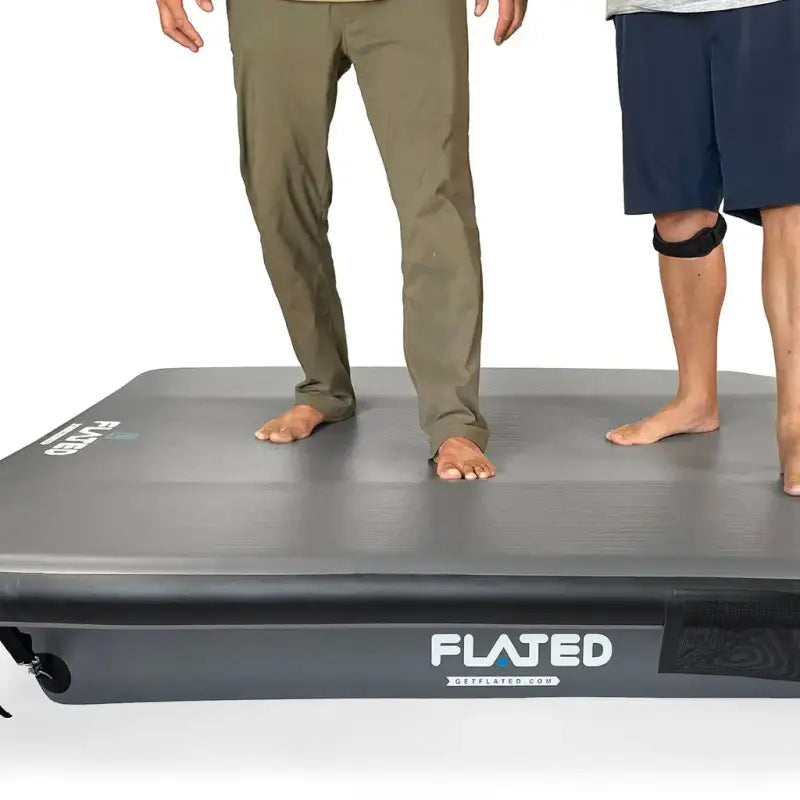 Two people standing on the 6' Cot - Portable Air-Deck, demonstrating its 500lbs weight support and durable construction.