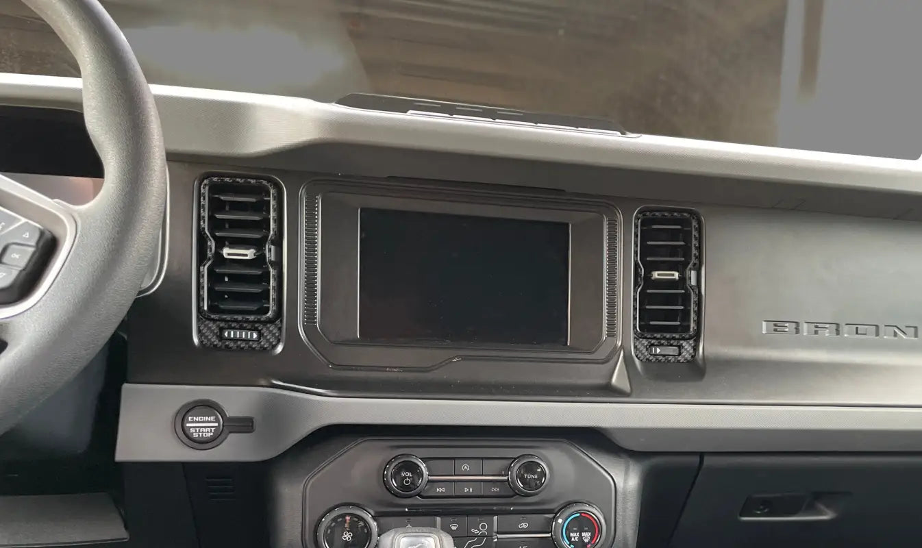Car dashboard with central display featuring vent accent overlays for Ford Bronco