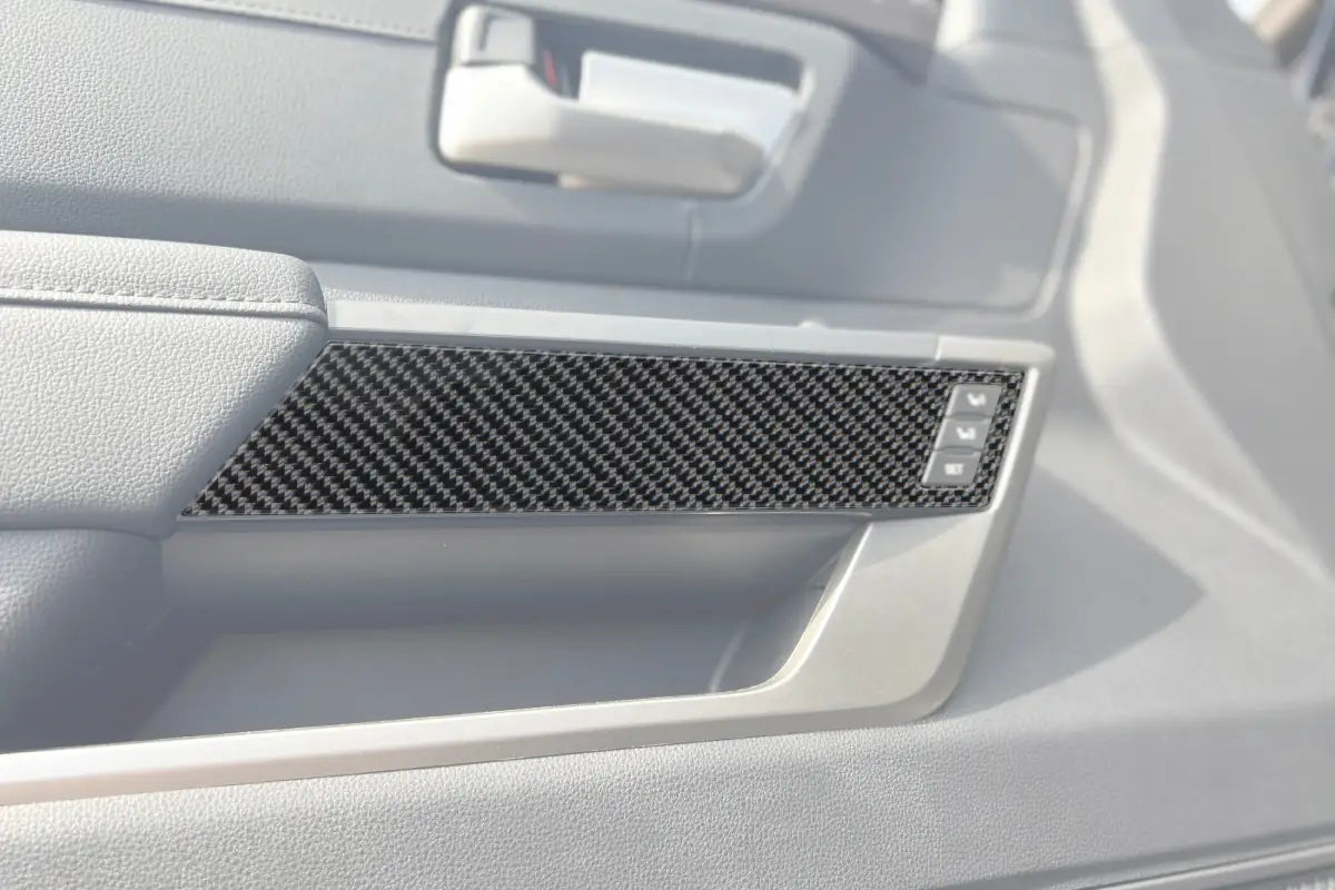 Carbon fiber arm rest accent trim installed on the interior door panel of a 2022-2024 Toyota Tundra or 2023-2024 Toyota Sequoia.