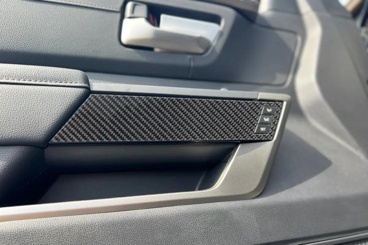 Close-up view of carbon fiber arm rest accent trim on the door panel of a Toyota Tundra or Sequoia, showcasing its sleek design.