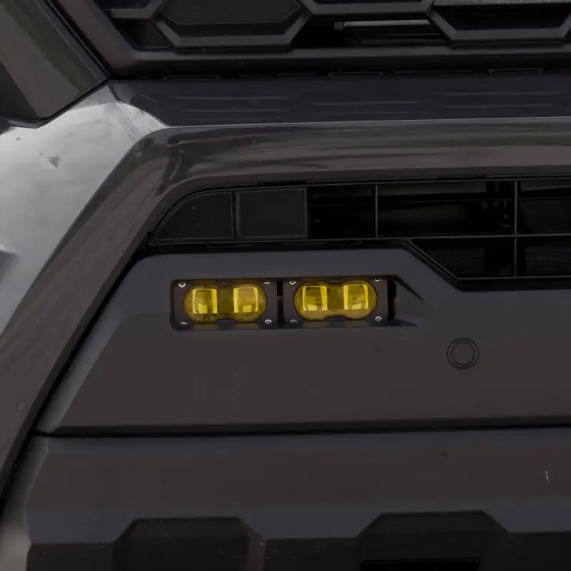 Installed Baja Designs S2 SAE amber fog lights on a 2024 Toyota Tacoma, seamlessly integrated into the front bumper.