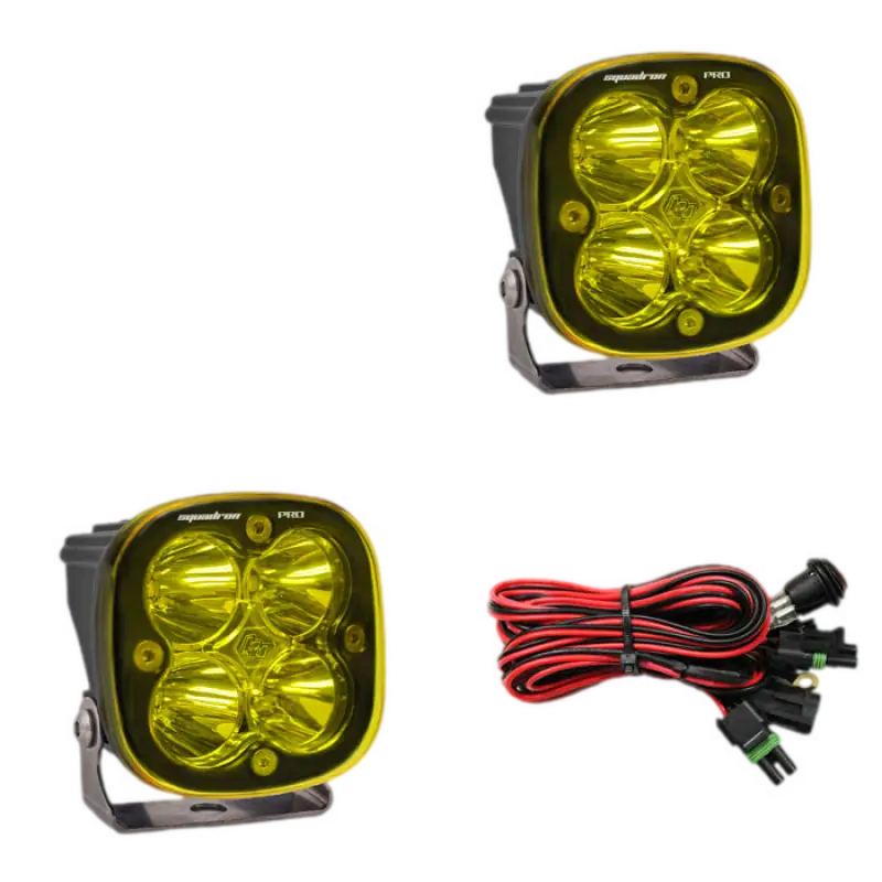 Baja Designs Squadron Pro LED light pods in black housing with amber lenses, featuring four LEDs and a wiring harness for off-road use.