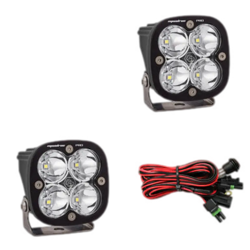 Baja Designs Squadron Pro LED light pods in black housing with clear lenses, showcasing four LEDs and a wiring harness for off-road use.