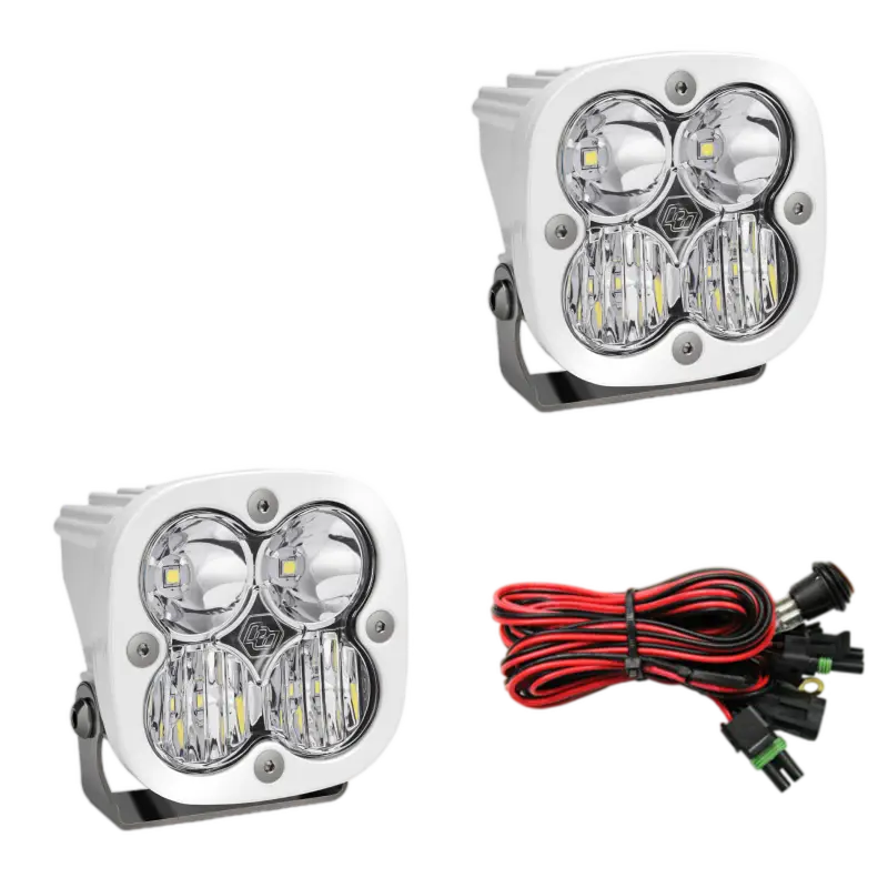 Baja Designs Squadron Pro LED light pods in white housing with clear lenses, designed for off-road lighting with included wiring harness.