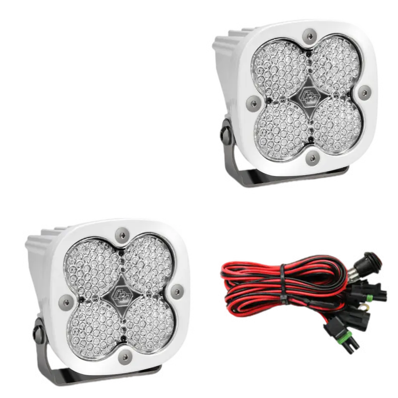 Baja Designs Squadron Pro LED light pods in white housing with clear lenses, showcasing four LEDs and a wiring harness for off-road use.