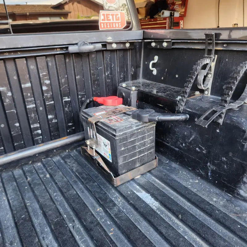 Rear truck bed view of a Toyota Tacoma with a relocated battery installed using the JETG Designs kit.