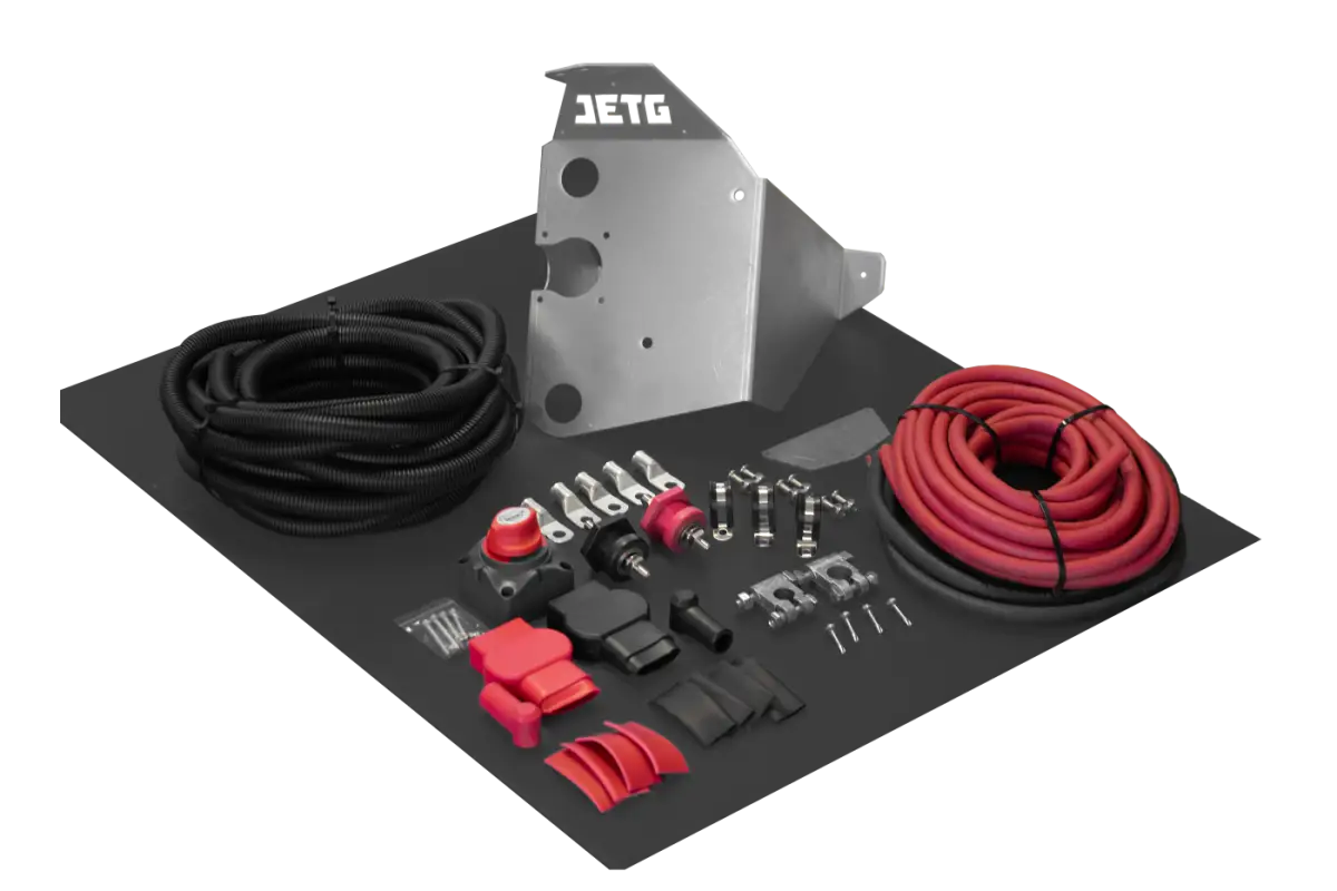 Toyota Tacoma battery relocate kit with all components, including cables, bracket, terminals, and protective covers, displayed on a black surface.