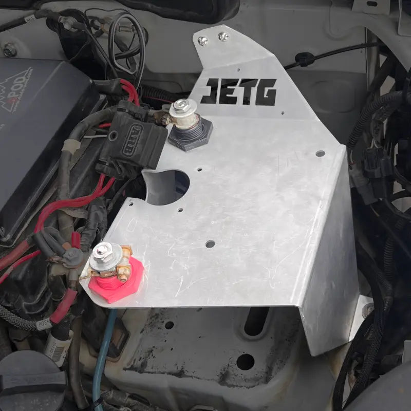 JETG Designs aluminum mounting bracket installed in the engine bay of a Toyota Tacoma as part of the battery relocate kit.
