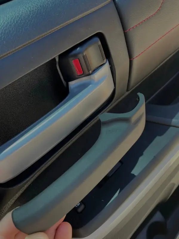 Tundra blackout door handle cover being installed over a factory handle, showcasing its precise 3D fit and stylish upgrade for Toyota Tundra interiors.