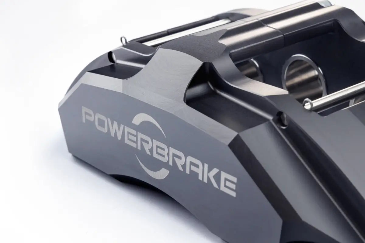 Close-up of the PowerBrake 6 piston caliper in grey finish, showcasing precision machining and branding.