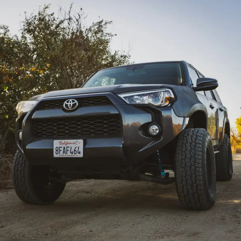Front view of a 5th Gen 4runner equipped with GX460 long travel suspension, parked on a dirt trail with lifted stance.