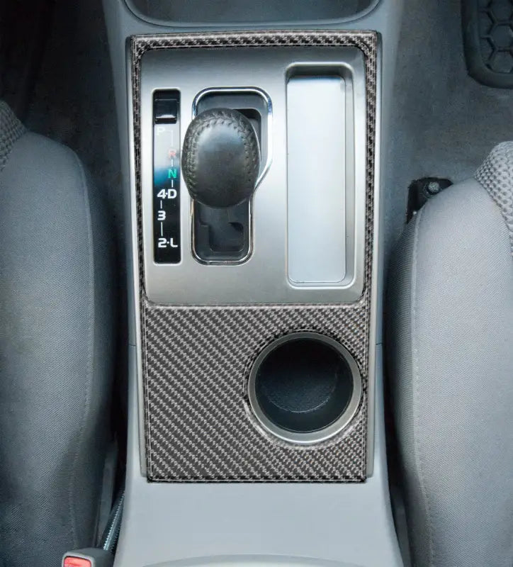 Close-up view of a carbon fiber center console accent overlay fitted on a 2005-2015 Toyota Tacoma, showcasing precise fit and modern style.