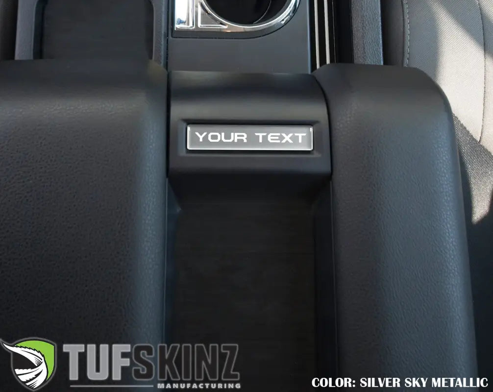 Reflective black shadow customizable center console badge installed in a 2014-2021 Toyota Tundra, adding a sleek and modern interior accent.