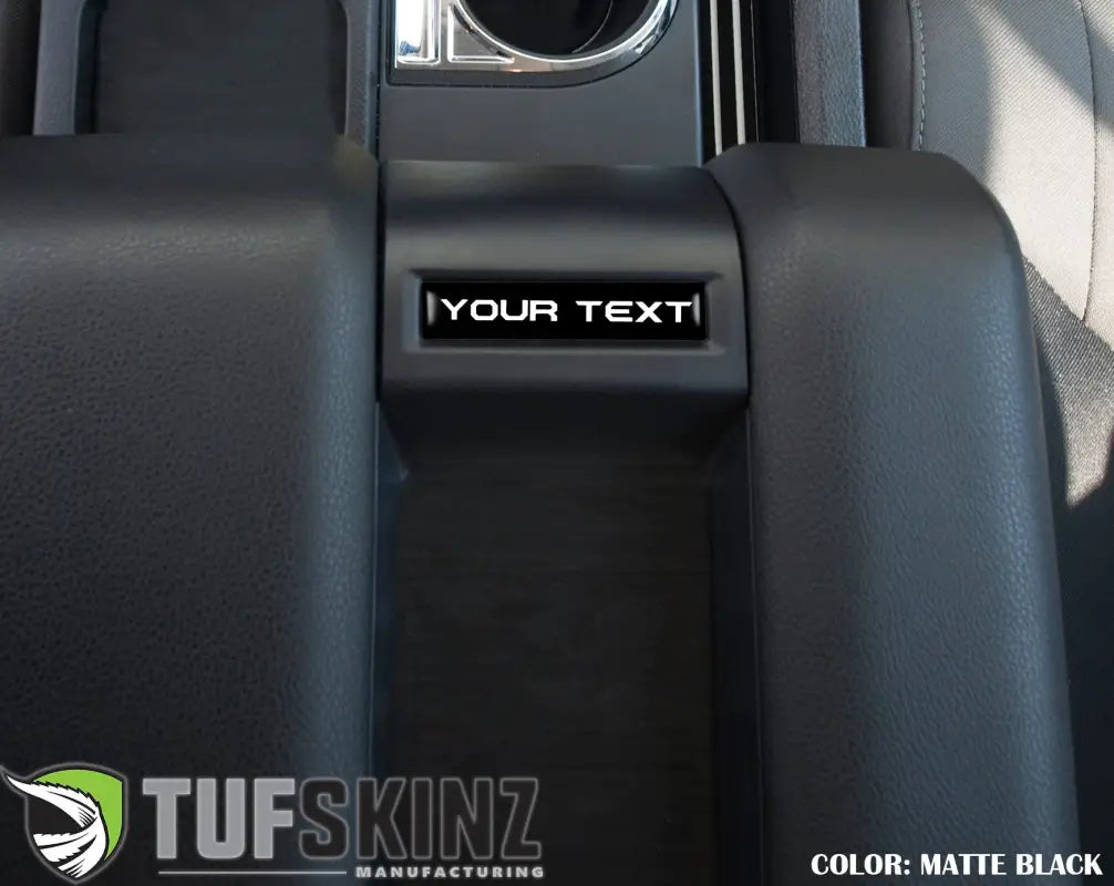 Matte black customizable center console badge installed in a 2014-2021 Toyota Tundra, adding a sleek interior accent.