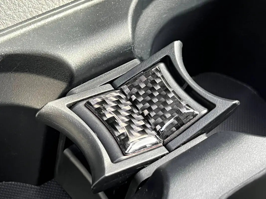 Close-up view of carbon fiber textured center console cup holder divider overlays fitted in a Toyota Tacoma 2016-2023.