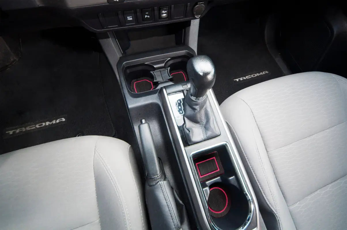 Close-up of center console cup holder inserts in a Toyota Tacoma, showcasing black foam material with red accents for a sleek look.
