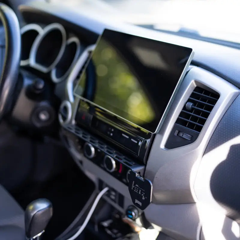 Toyota Tacoma interior with a modular accessory mount installed below the dashboard screen, ready for customization.