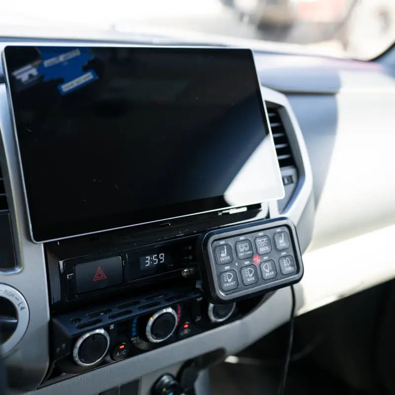 Dash-mounted modular accessory mount holding a control panel for additional vehicle functions in a Toyota Tacoma.