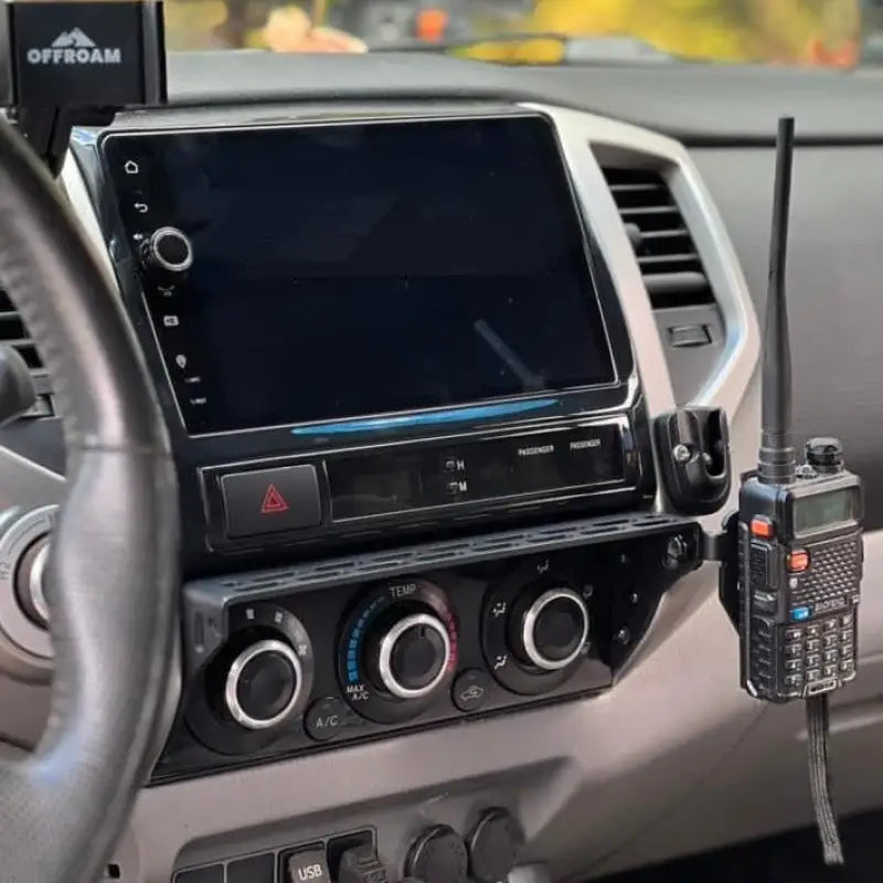 Toyota Tacoma dash mount with a two-way radio and phone holder attached, highlighting its utility for off-road enthusiasts.