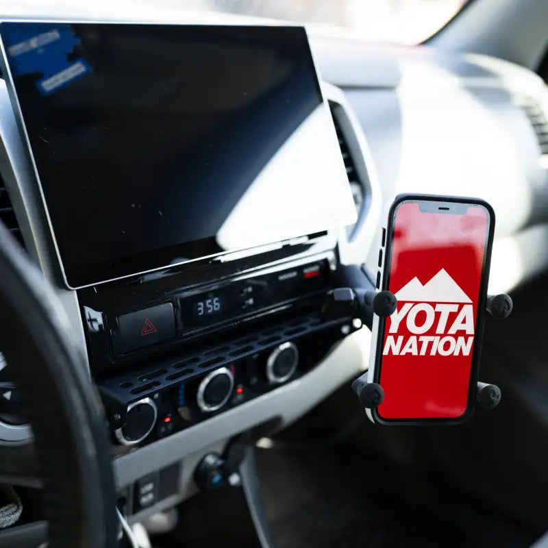 Tacoma dash mount with a smartphone holder displaying 'Yota Nation' logo, securely attached to the modular accessory mount.