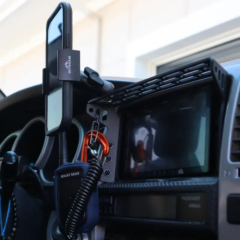 4th Gen 4Runner modular dash mount in vehicle, holding a phone, walkie-talkie, and keychain for organized accessory management.