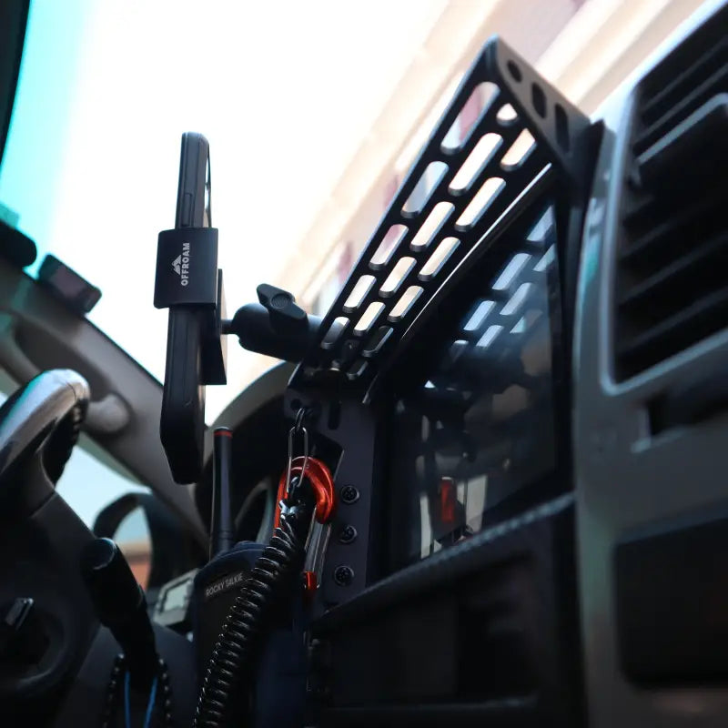 Side view of 4th Gen 4Runner modular dash mount in vehicle, holding a phone and walkie-talkie, showcasing its ergonomic design.