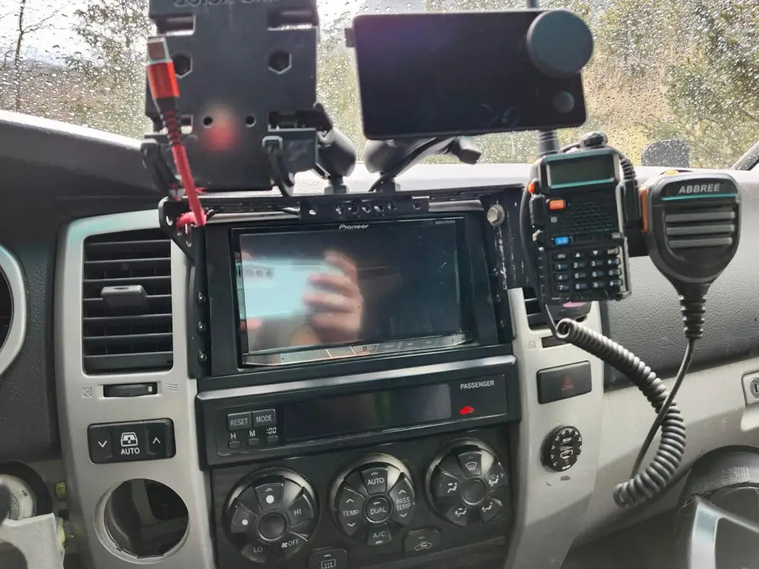 4th Gen 4Runner modular dash mount in use, holding a phone, walkie-talkie, and GPS device on the center console.