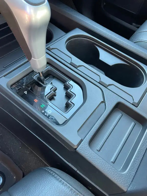 Black Tundra Chrome Delete Kit installed on a vehicle console, featuring upgraded trim around cup holders and gear shifter.