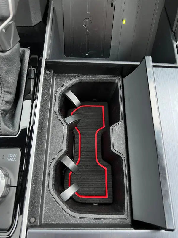 Close-up view of a cup holder foam insert with red trim fitted in the center console of a Toyota Tundra or Sequoia.