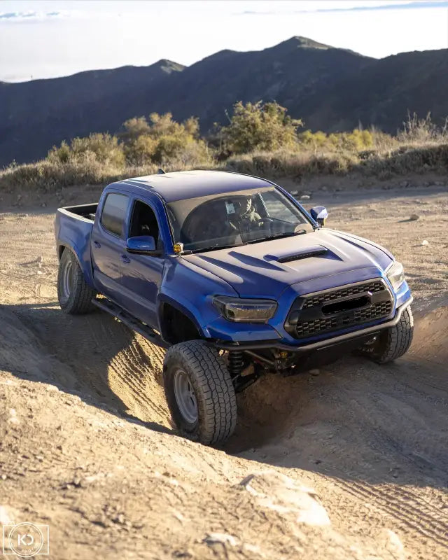 Blue Toyota Tacoma off-road truck with custom pre runner bumper and relocated power steering brackets