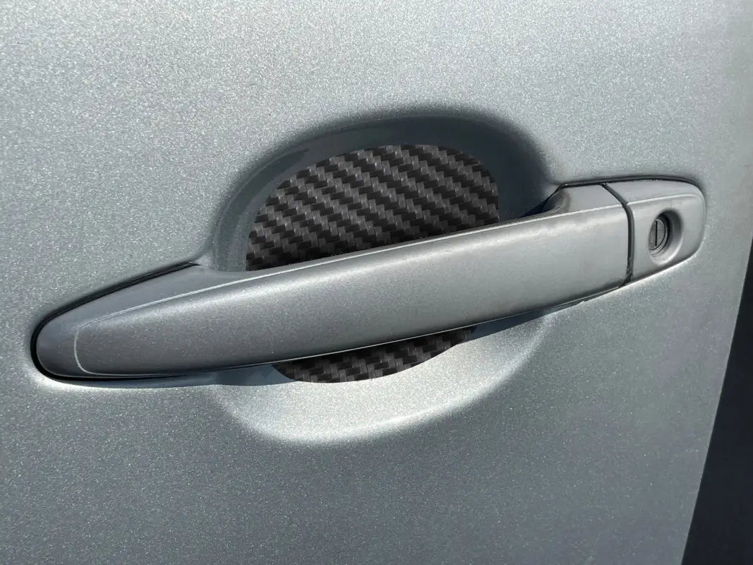 Carbon fiber-style door handle protective insert installed on a silver Toyota Tacoma, fits 2005-2015 and 2024-up models.