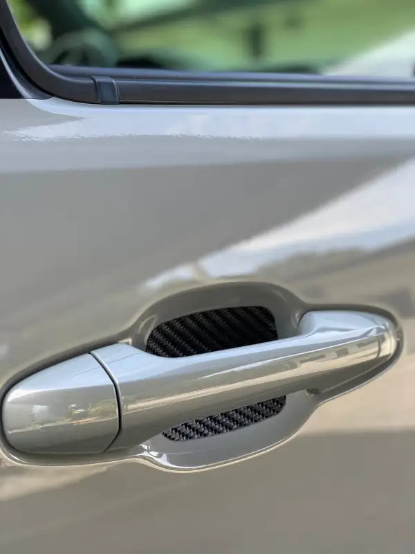 Carbon fiber-style door handle protective insert installed on a Toyota Tacoma or 4Runner, adding a modern and durable finish.