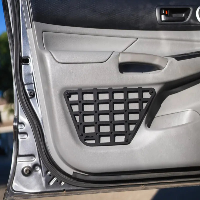 2nd Gen Tacoma door molle panel installed on a 2012-2015 model, showcasing a black powder-coated aluminum grid design.