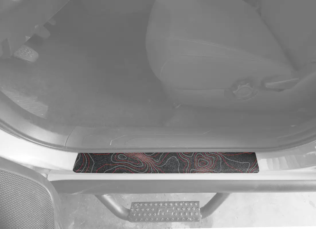 Black textured door sill overlay with red and gray contour map design for 2005-2023 Toyota Tacoma, bold and durable.