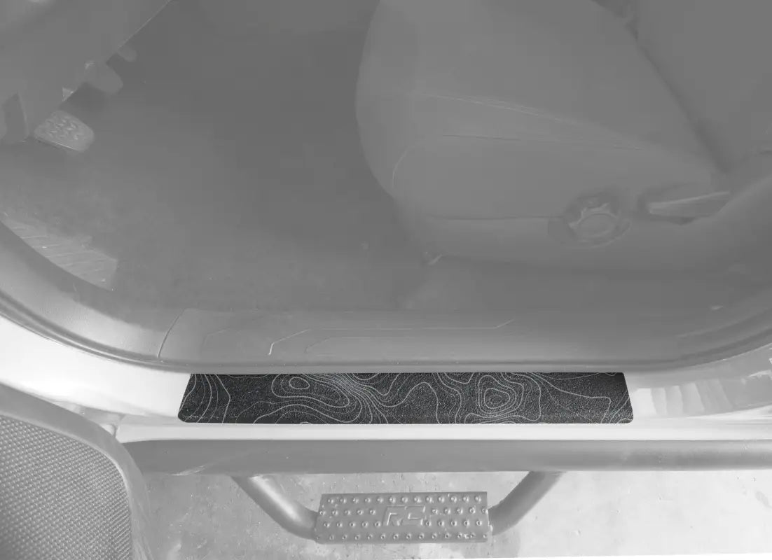 Black textured door sill overlay with gray contour map design for 2005-2023 Toyota Tacoma, stylish and protective.
