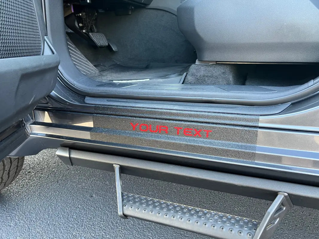 Customizable black door sill overlay with red 'YOUR TEXT' lettering installed on a Toyota Sequoia, offering a personalized touch.
