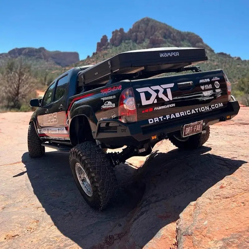 DRT high clearance rear bumper installed on a lifted 2005-2015 Toyota Tacoma with off-road setup, showcasing enhanced departure angle and rugged design.