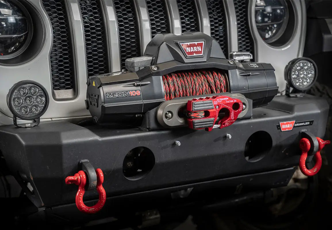 Red Factor 55 Ultra Hook mounted on a WARN winch system on a Jeep bumper, showcasing its off-road application and closed system design.